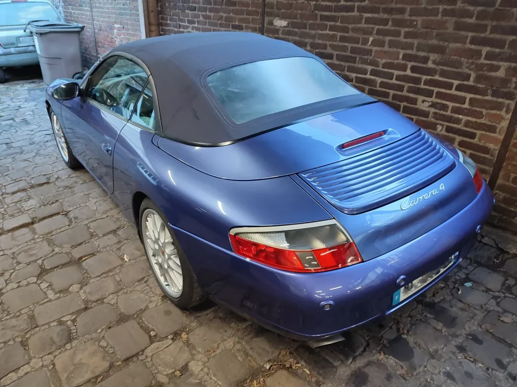 Porsche 911 996 Cabriolet Carrera 4 bleue devant le mur de brique de l’atelier Autorosati